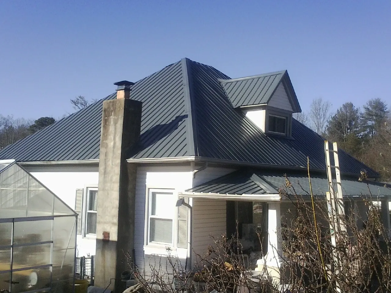 Dark blue standing seam metal roof on a white farmhouse with dormer — Slate & Tile Roof Repair by Roofing Brothers in Julian