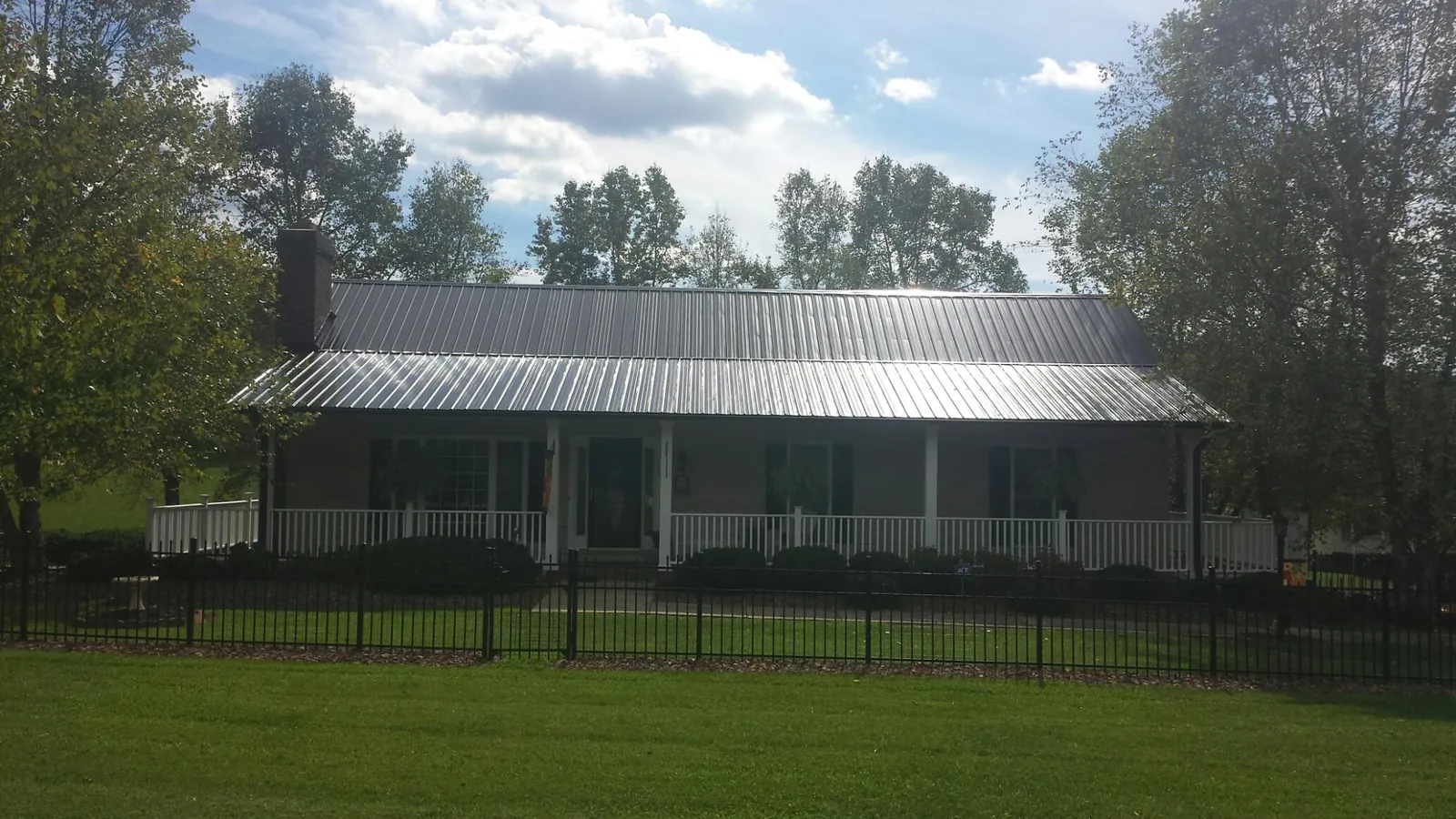 Gray metal roof on a brick ranch with a full width front porch — Gutter Guard Installation work by our crew in Julian