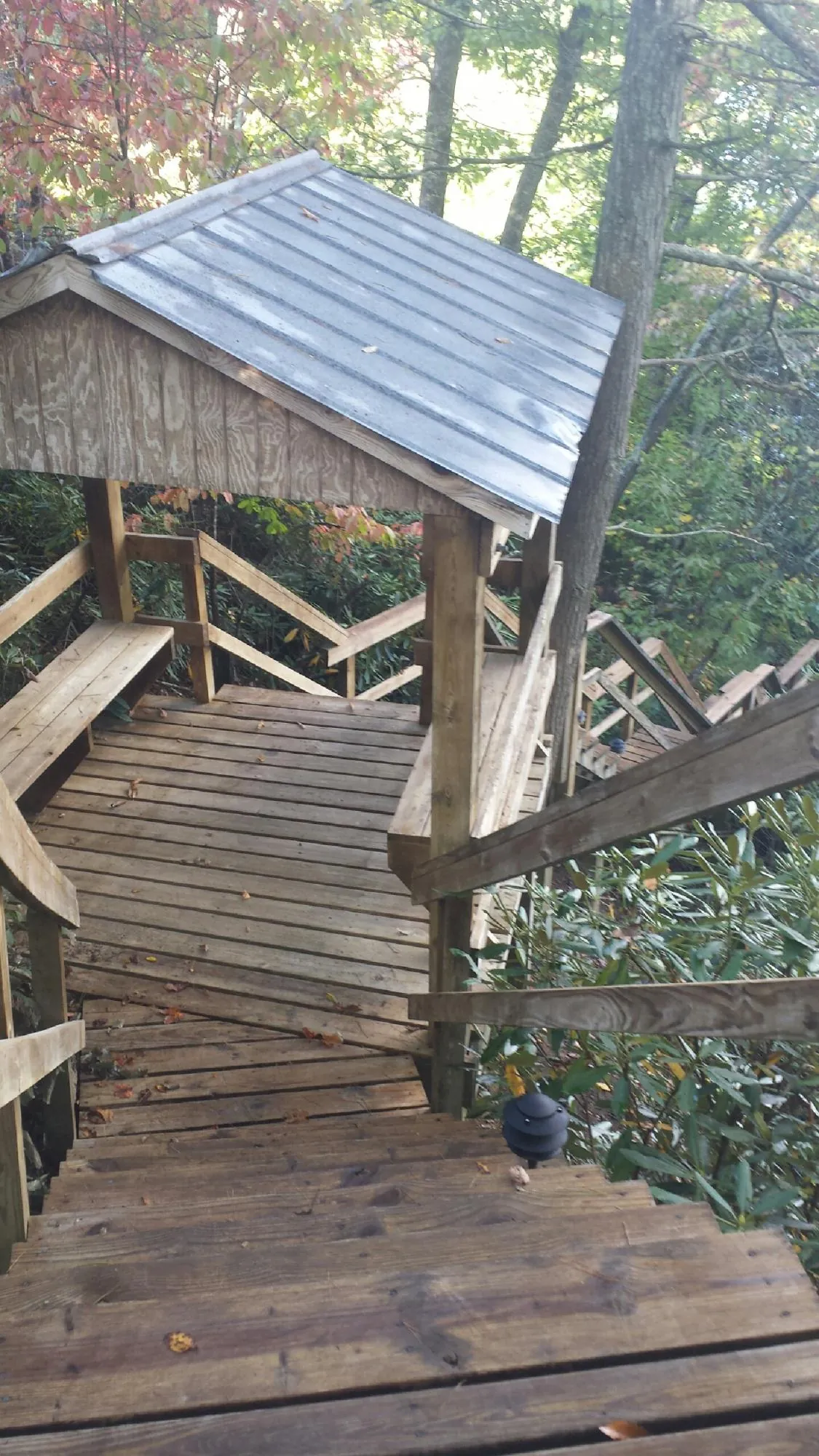 Metal roofed shelter over wooden steps on a wooded walkway — Skylight Repair & Installation work by our crew in Julian